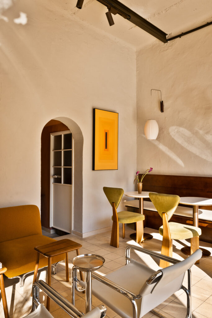 Lima Cafe seating area with an arched doorway, green chairs and wall lamps.