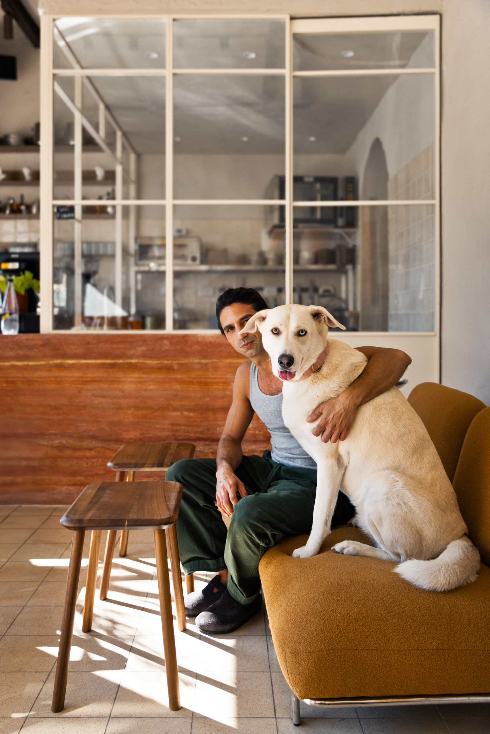Person sitting with a dog beside a glazed partition at Lima Cafe.